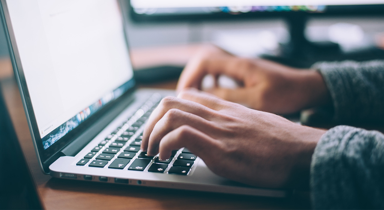 Mãos a escrever no teclado de um computador